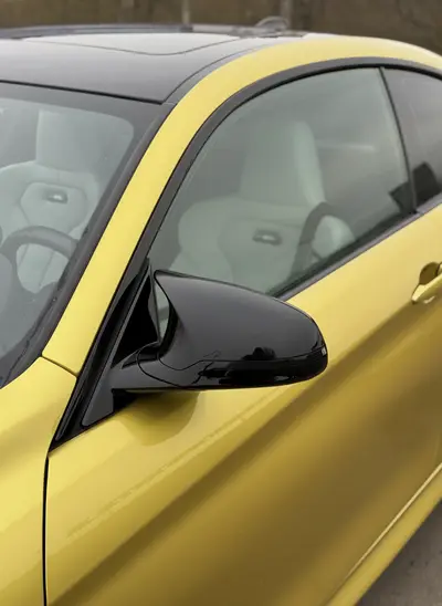 Боковое зеркало и кузов жёлтого BMW M4 — крупный план